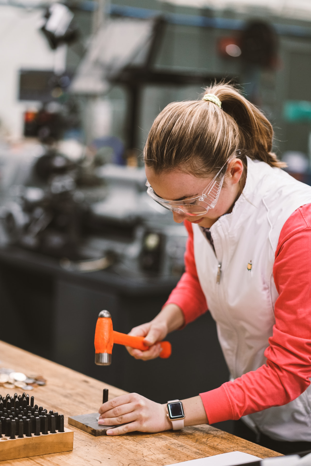 Michelle stamping custom ball markers in the UTD workshop